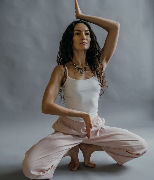 Woman in a graceful yoga pose, embodying tranquility and balance in a dark studio.